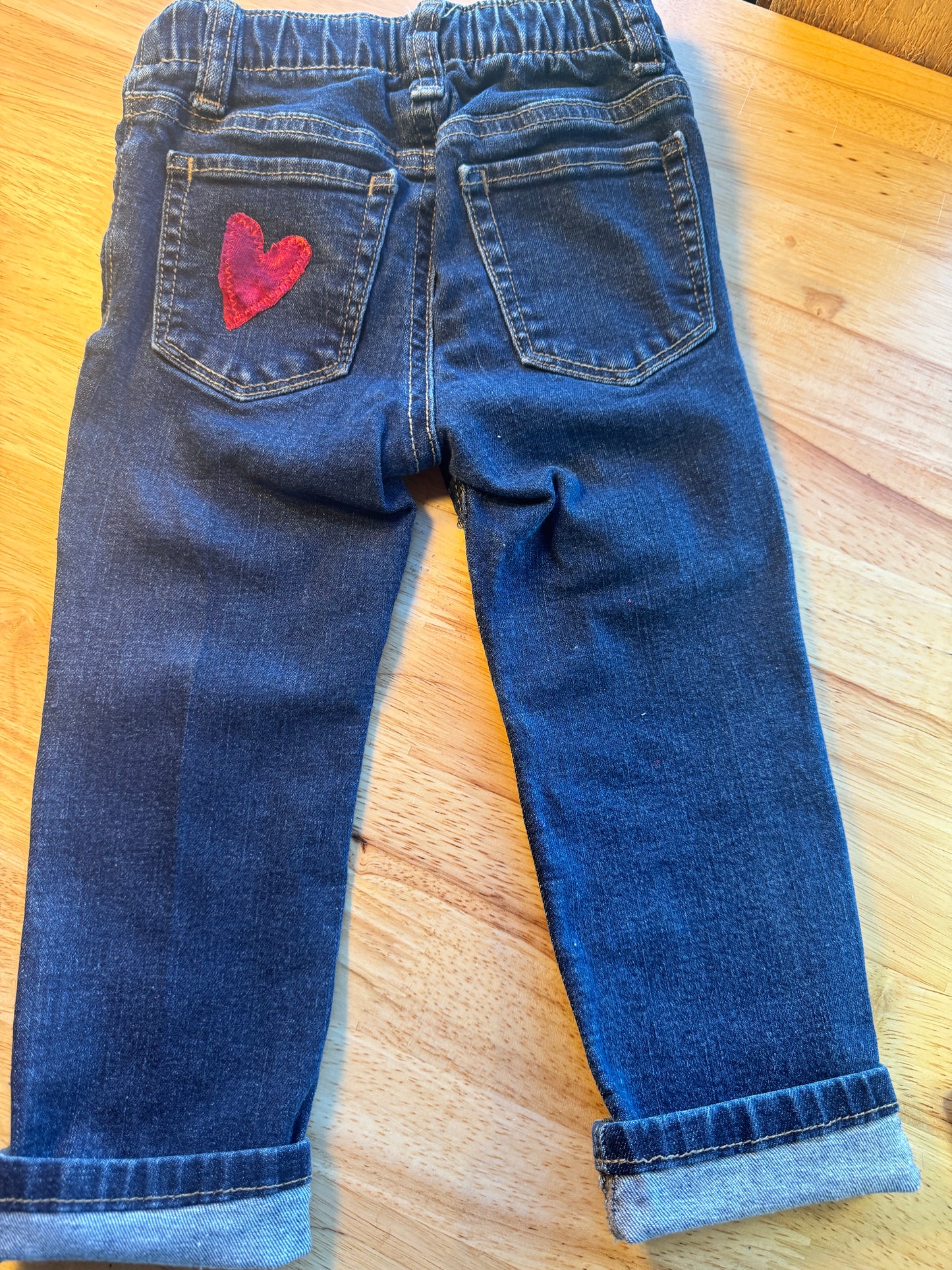 Pair of blue jeans with a red logo on a wooden surface