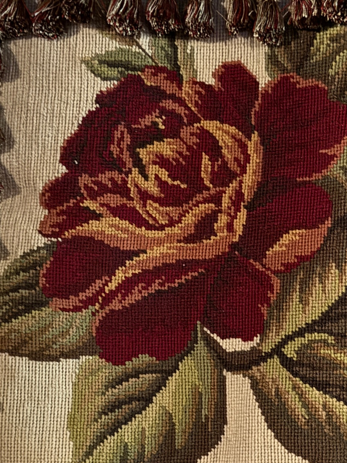 Close-up of a embroidered rose on fabric with a textured border.