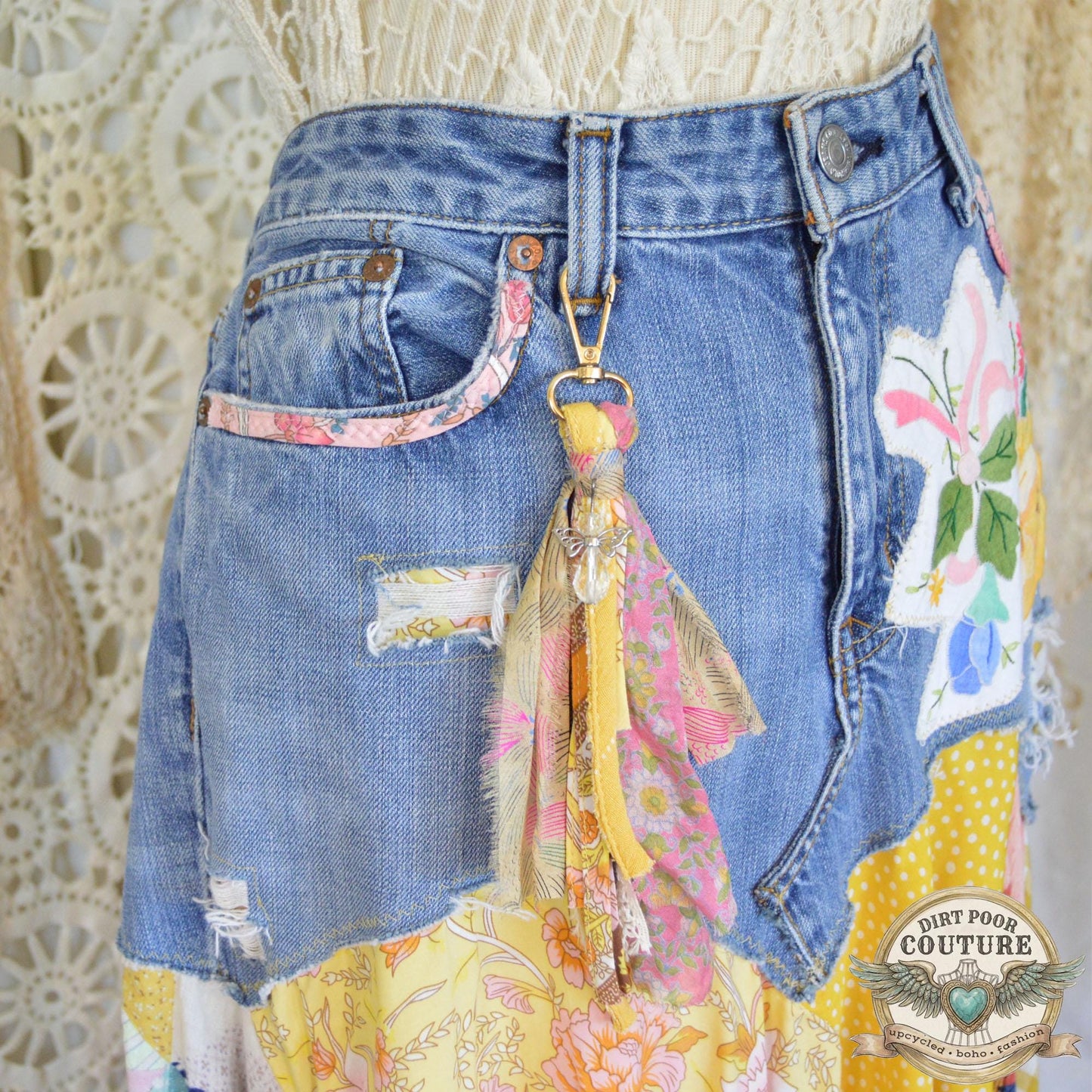 Close-up of a vintage floral placemat applique and a fabric-trimmed pocket on the light-wash denim base