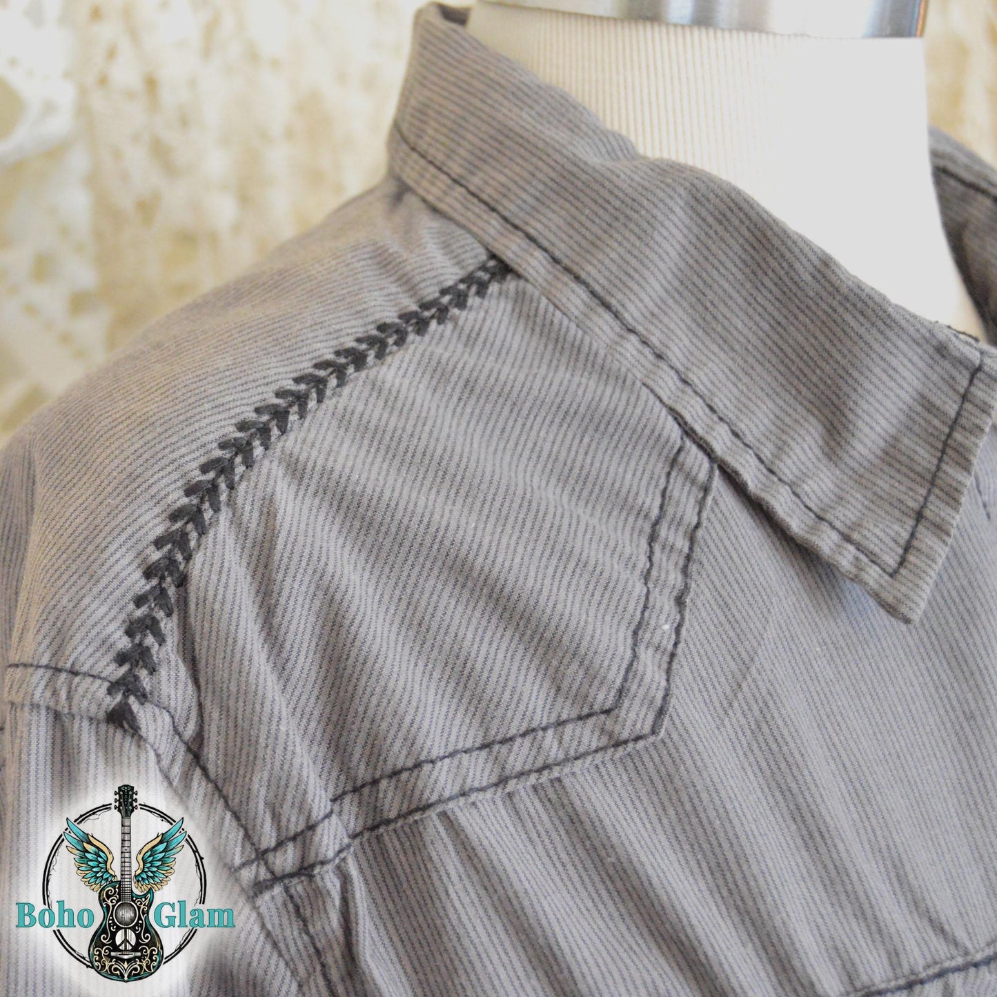 Close up of the gray corduroy fabric highlighting the black decorative western embroidery along the shoulder seam.
