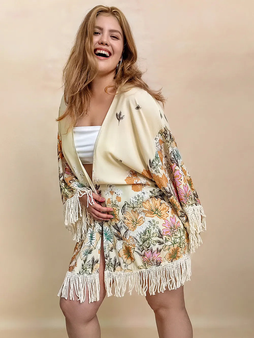 Woman wearing a floral kimono with fringes on a beige background