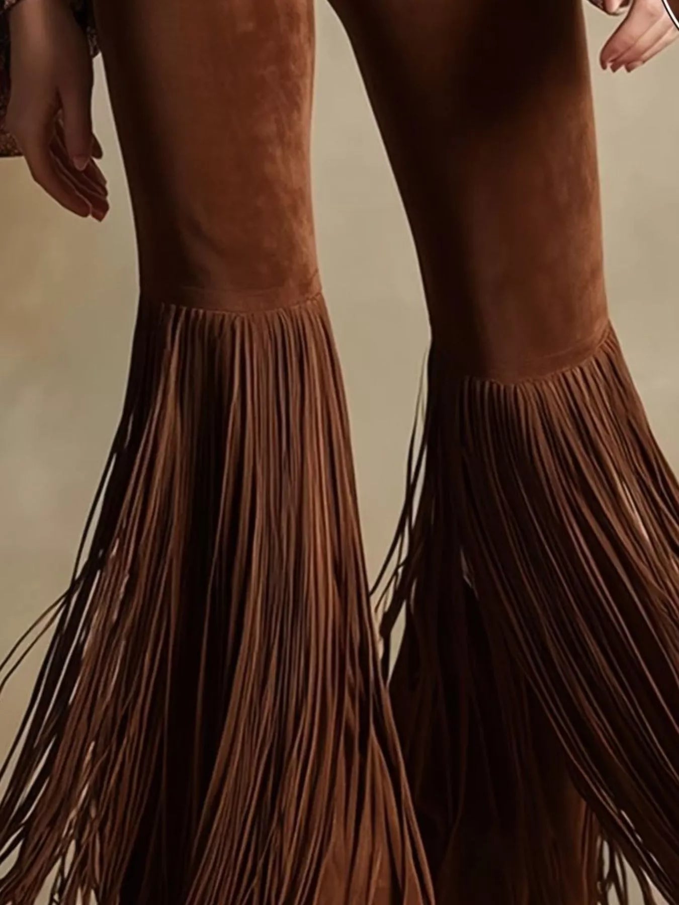 Brown suede fringe boots on a neutral background