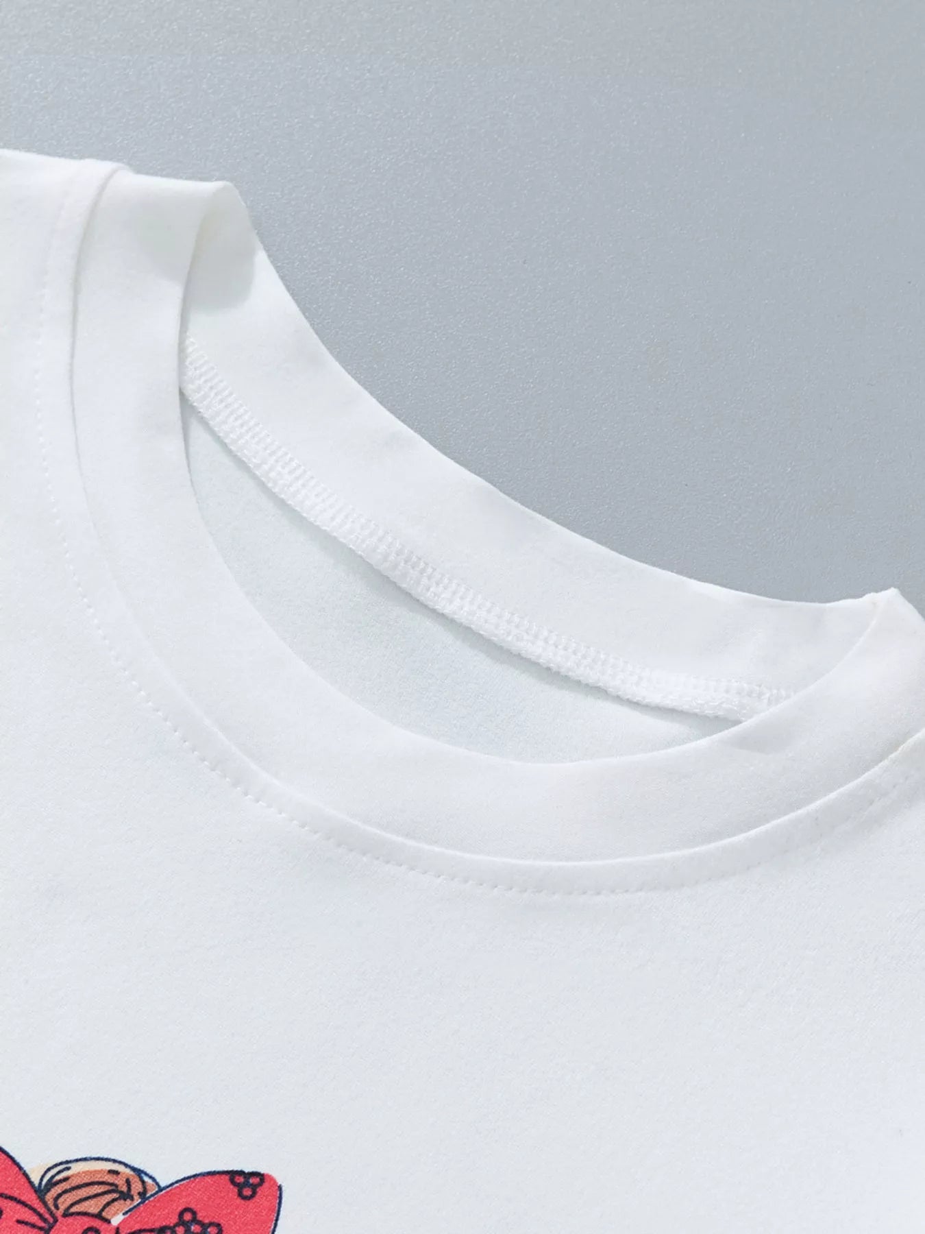 Close-up of a white t-shirt with a red design on a gray background