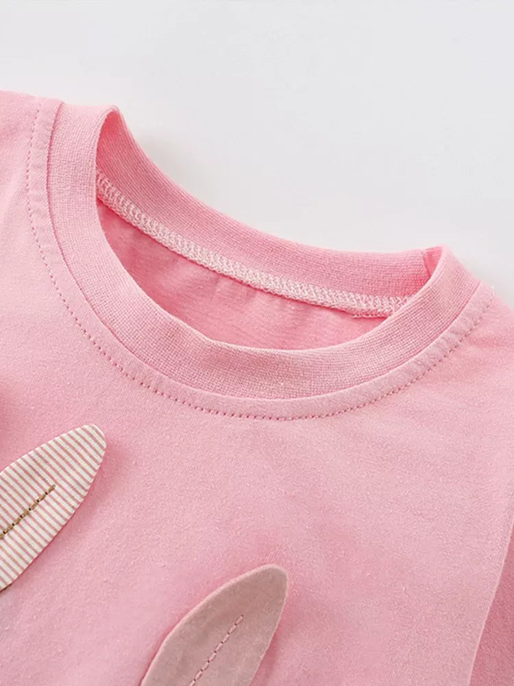 Close-up of a pink garment with a collar and sleeve details on a light gray background