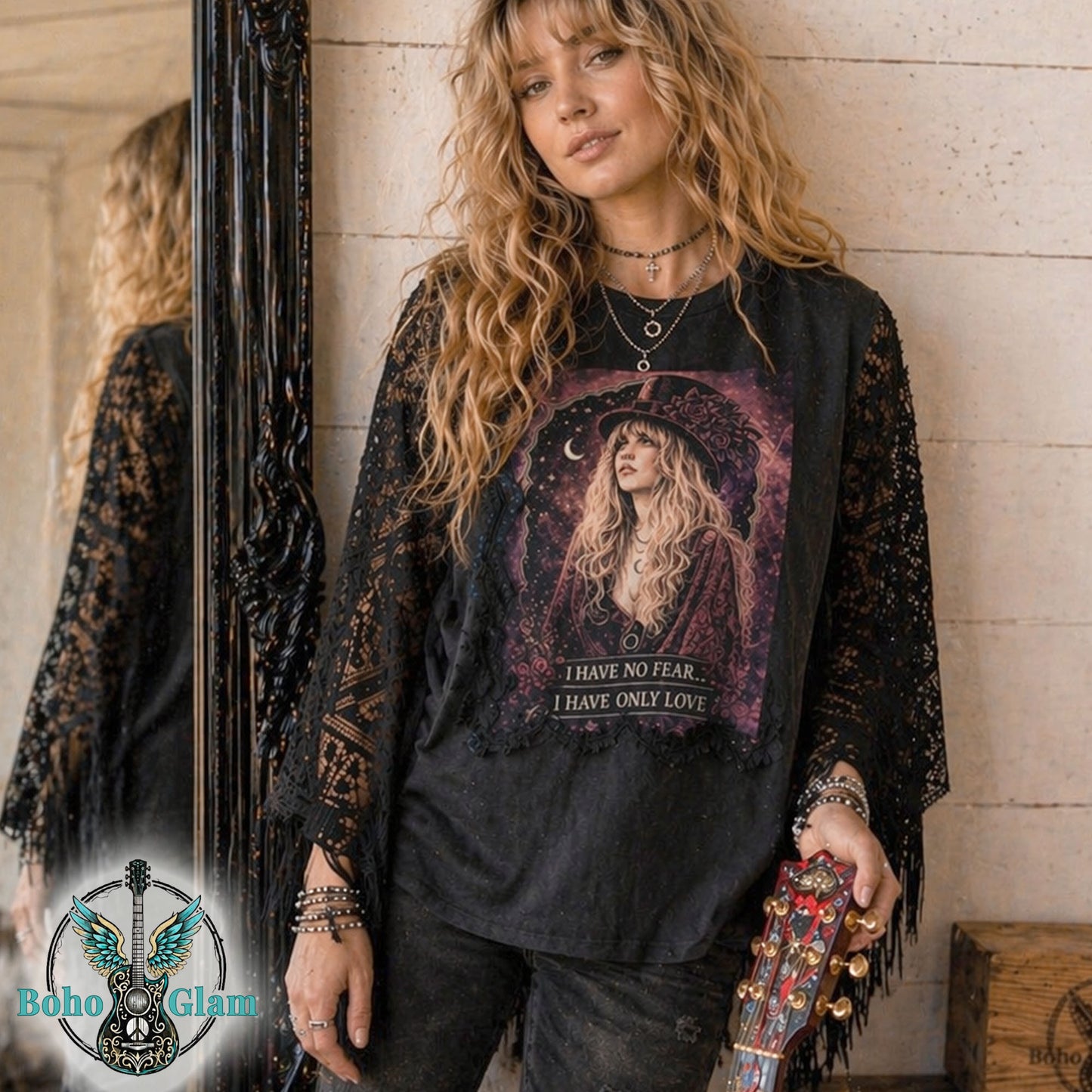 Woman wearing a black lace-trimmed shirt with a graphic design, standing against a wooden wall.