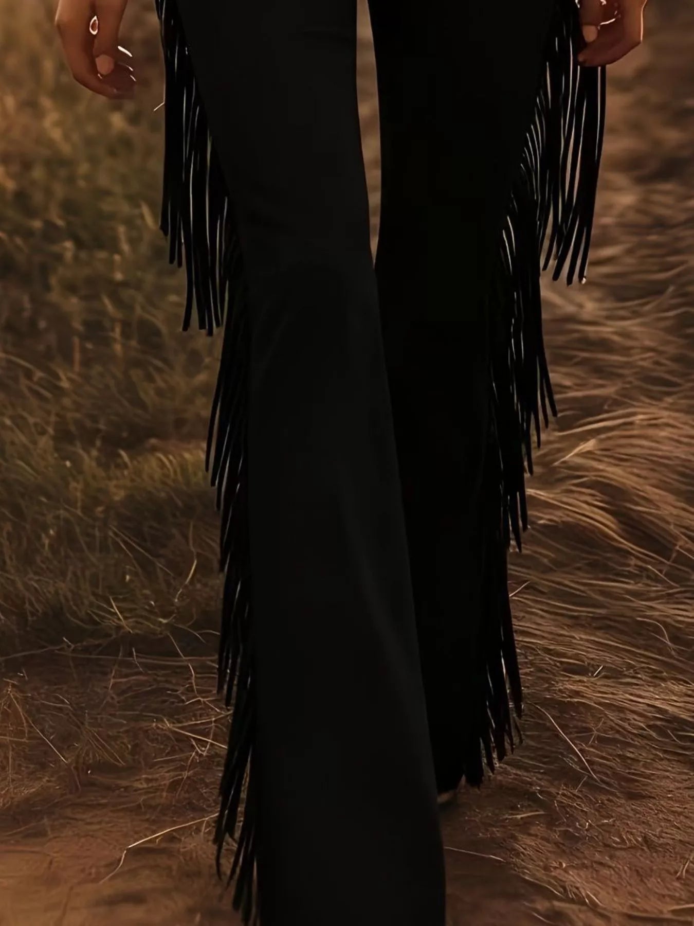 Black fringe dress on a person standing in a natural setting with grass and earth tones.