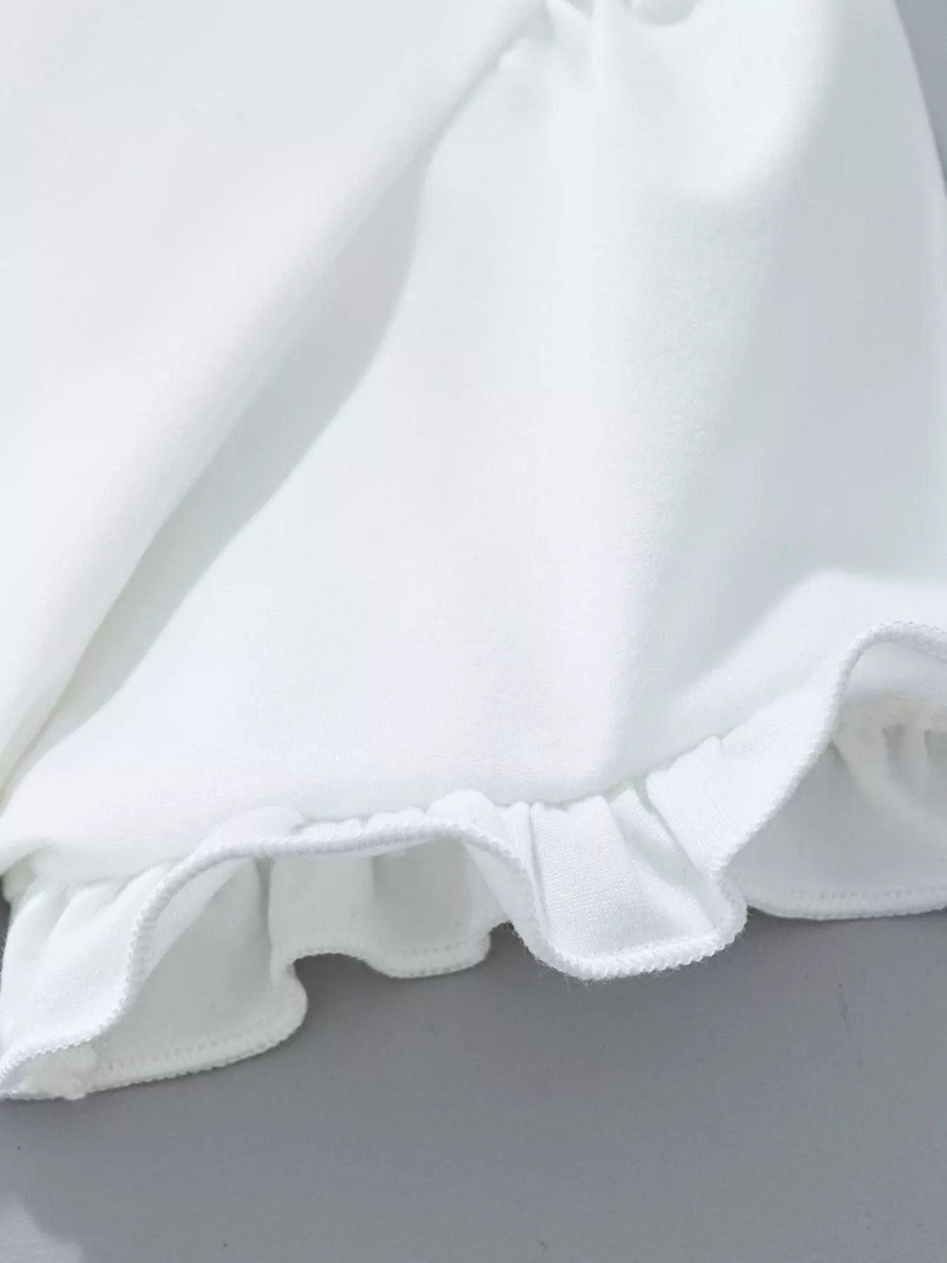 Close-up of a white ruffled fabric on a gray background