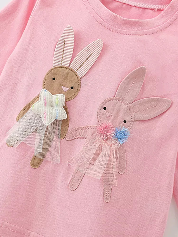Pink shirt with bunny rabbit appliqués on a plain background