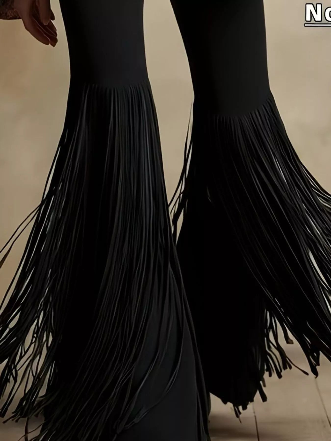 Black fringe pants on a neutral background
