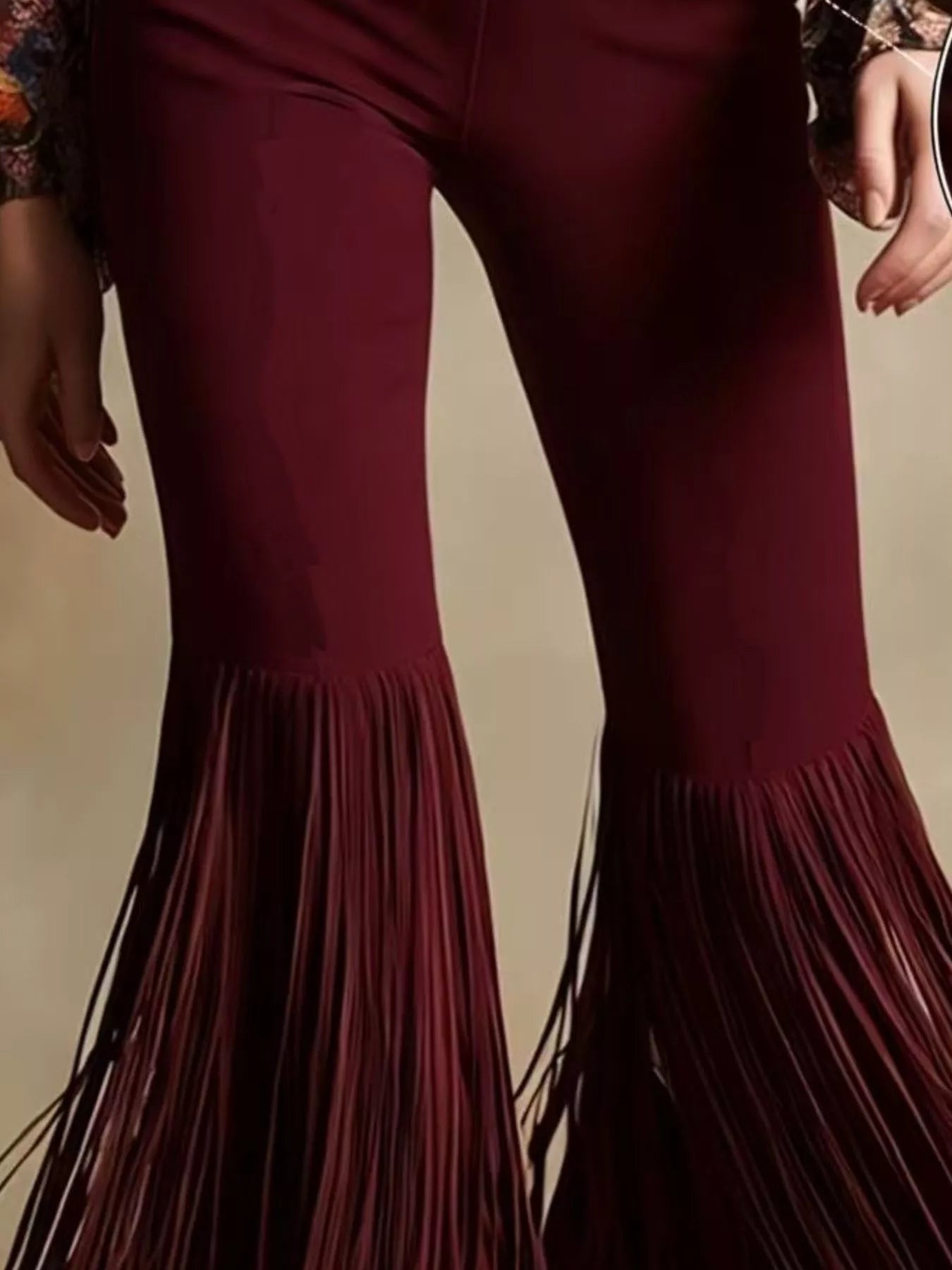 Maroon bell-bottom pants with fringe details on a neutral background