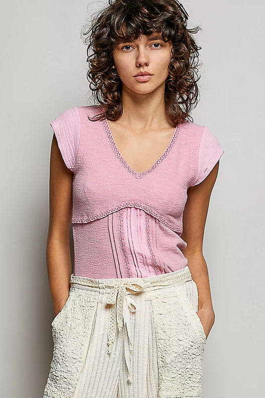 Woman wearing a pink top and white pants against a plain background