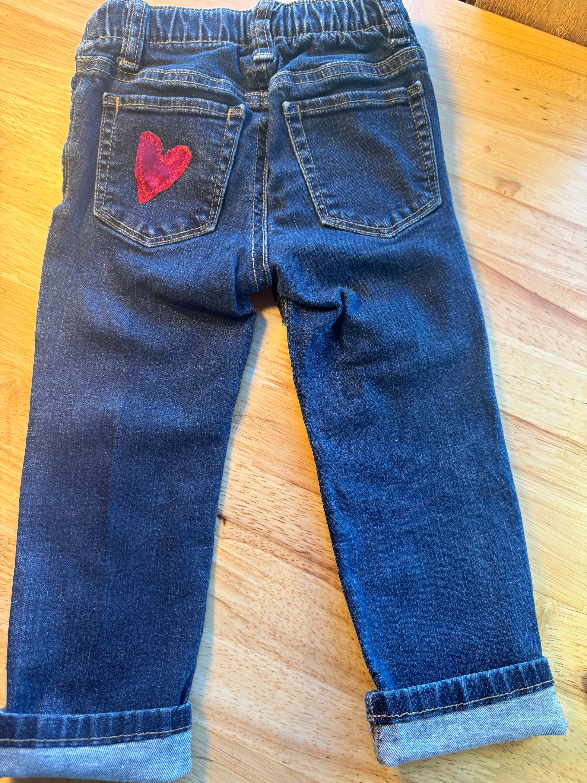 Pair of blue jeans with a red logo on a wooden surface