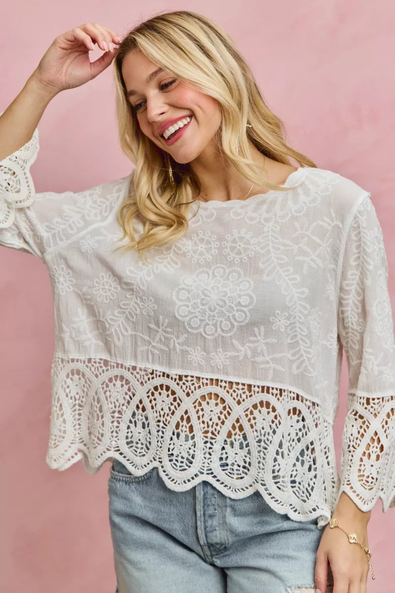 Woman wearing a white lace blouse against a pink background