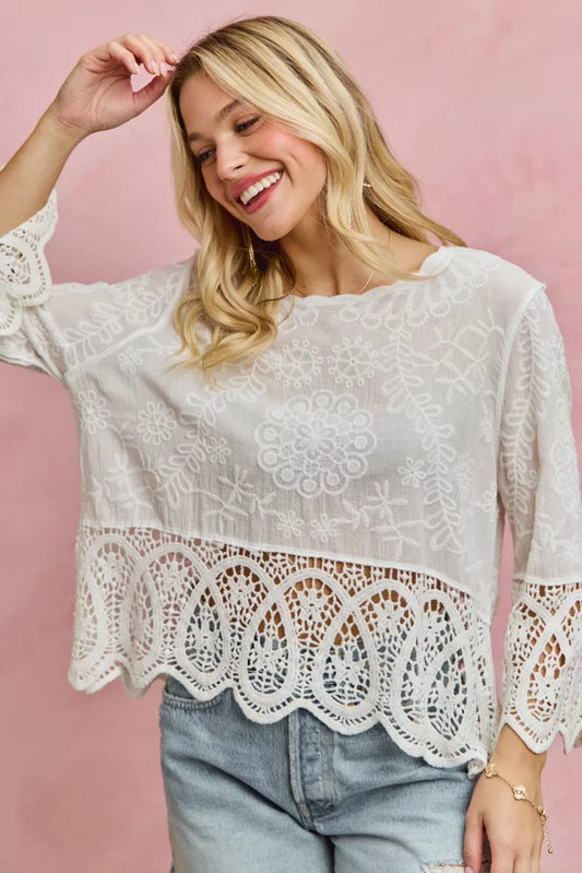 Woman wearing a white lace blouse against a pink background