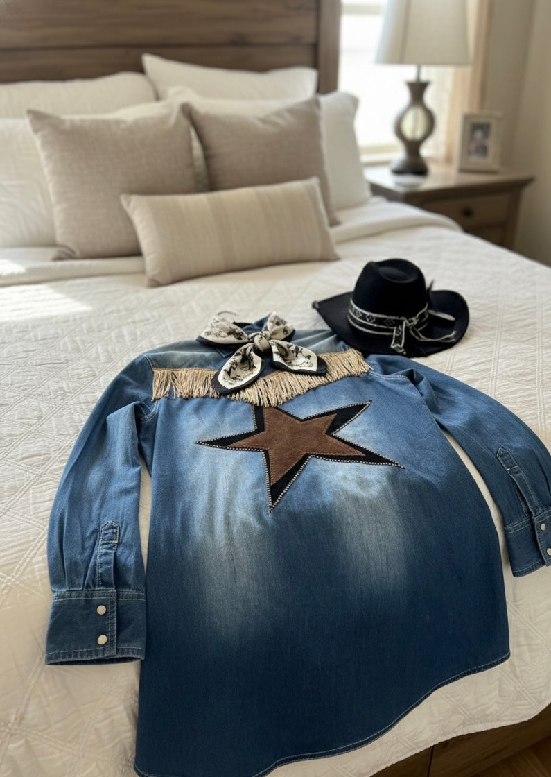 Blue denim jacket with a star design on a bed in a bedroom setting.