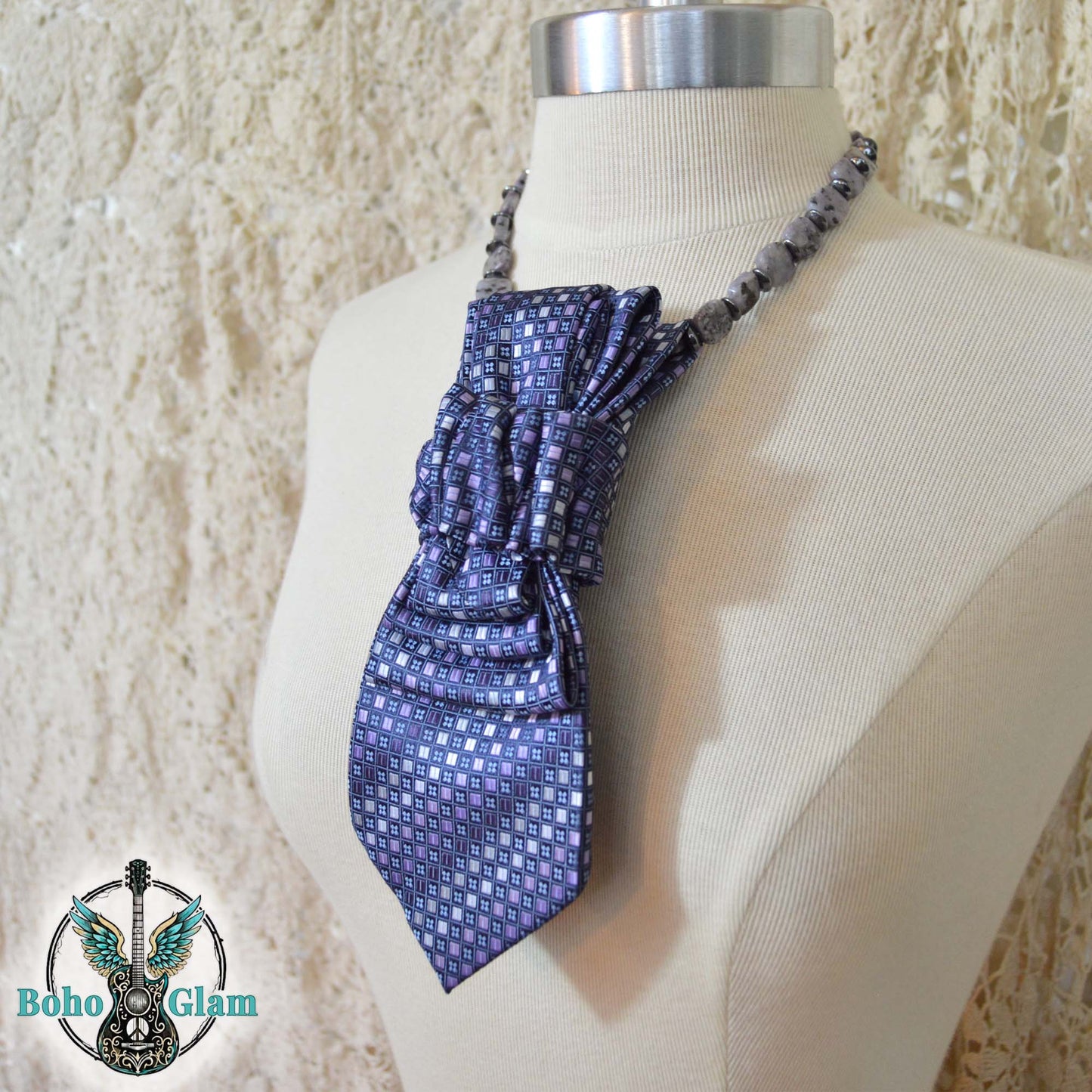 Blue patterned scarf tied around a mannequin with a textured beige background