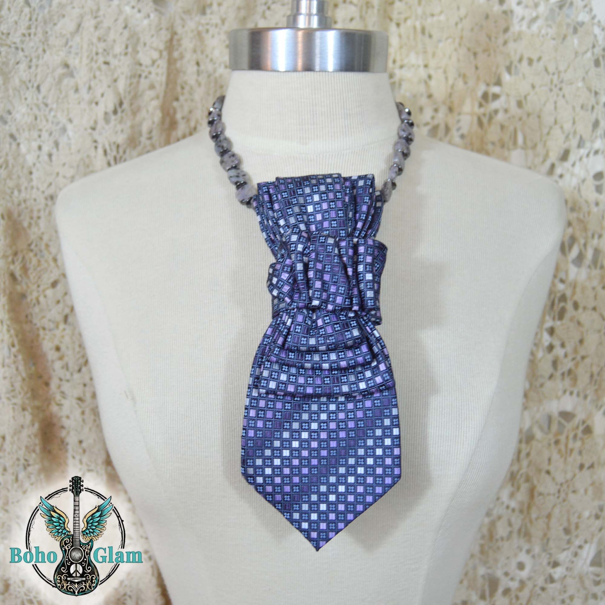 Blue patterned scarf on a mannequin with a textured beige background