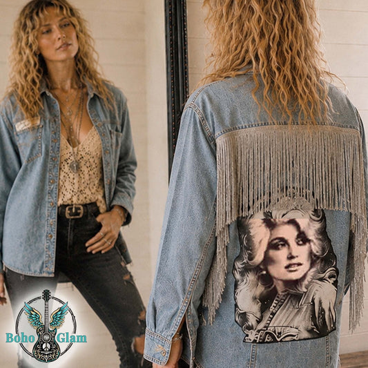 Woman wearing a denim jacket with fringe and a graphic design, standing in front of a mirror.