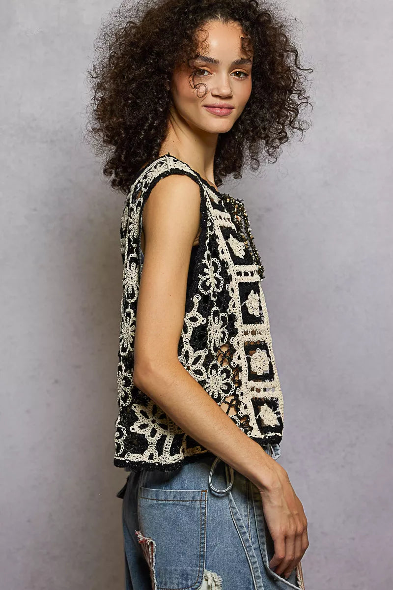 Woman wearing a sleeveless patterned top and jeans against a plain background