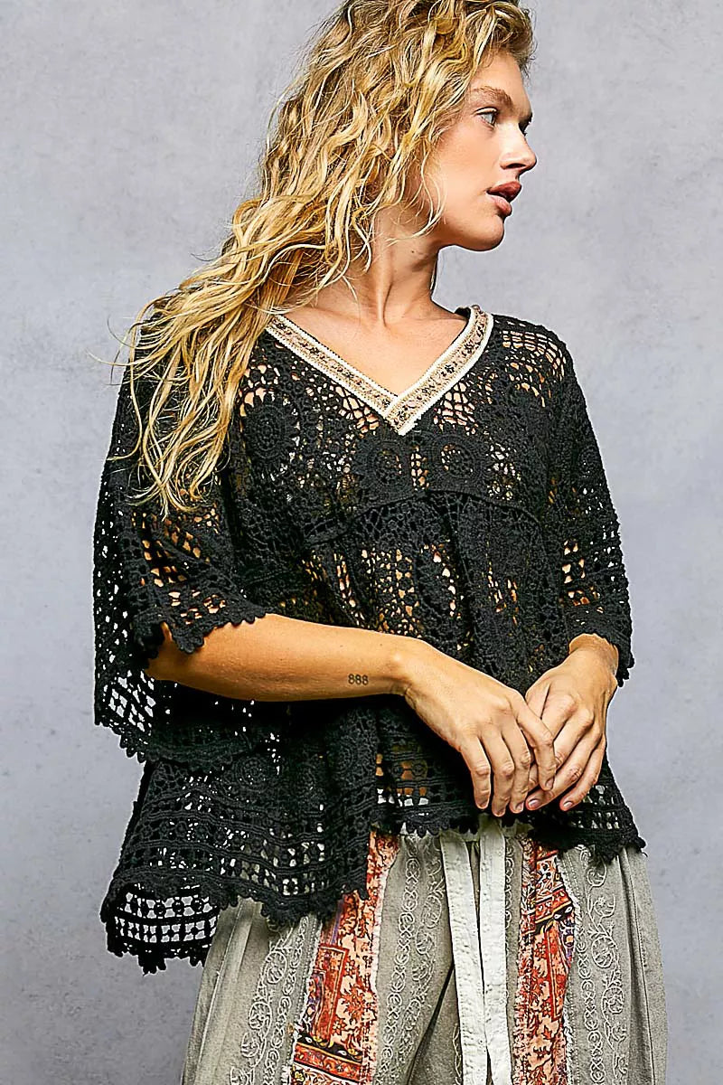 Woman wearing a black crochet top with a gray background
