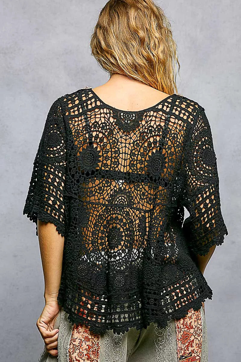 Black crochet top worn by a person on a gray background ( back view)