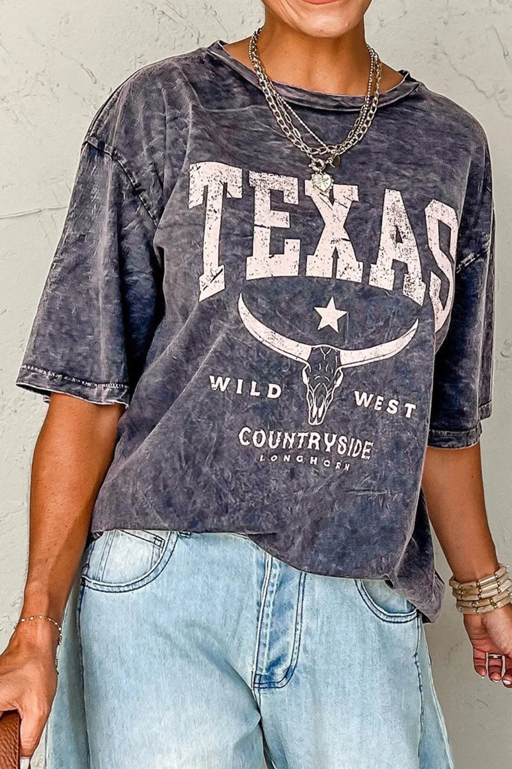Person wearing a graphic t-shirt with 'Texas Wild West Countryside' design.