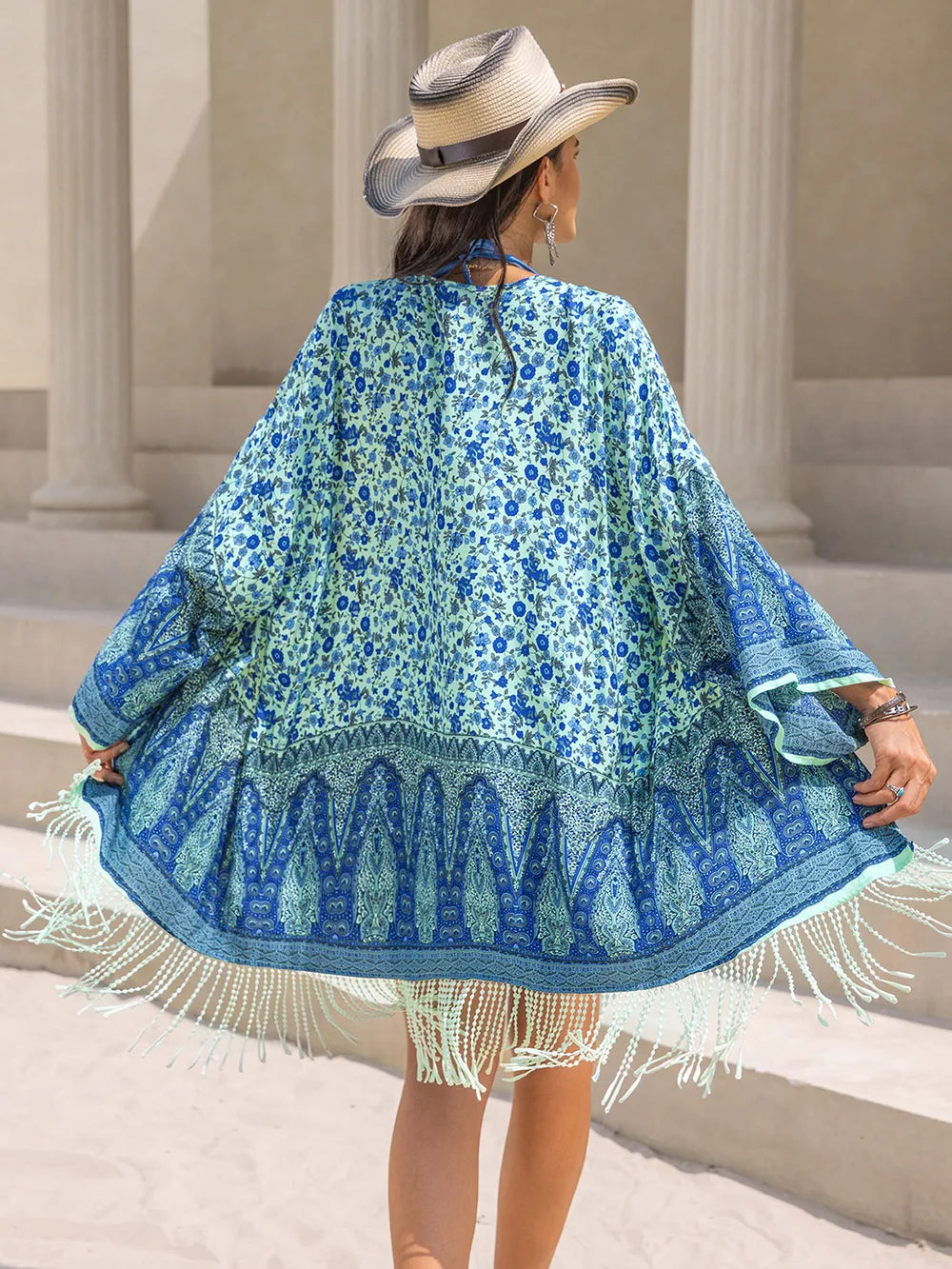 Woman wearing a blue floral kimono with fringe in an outdoor setting