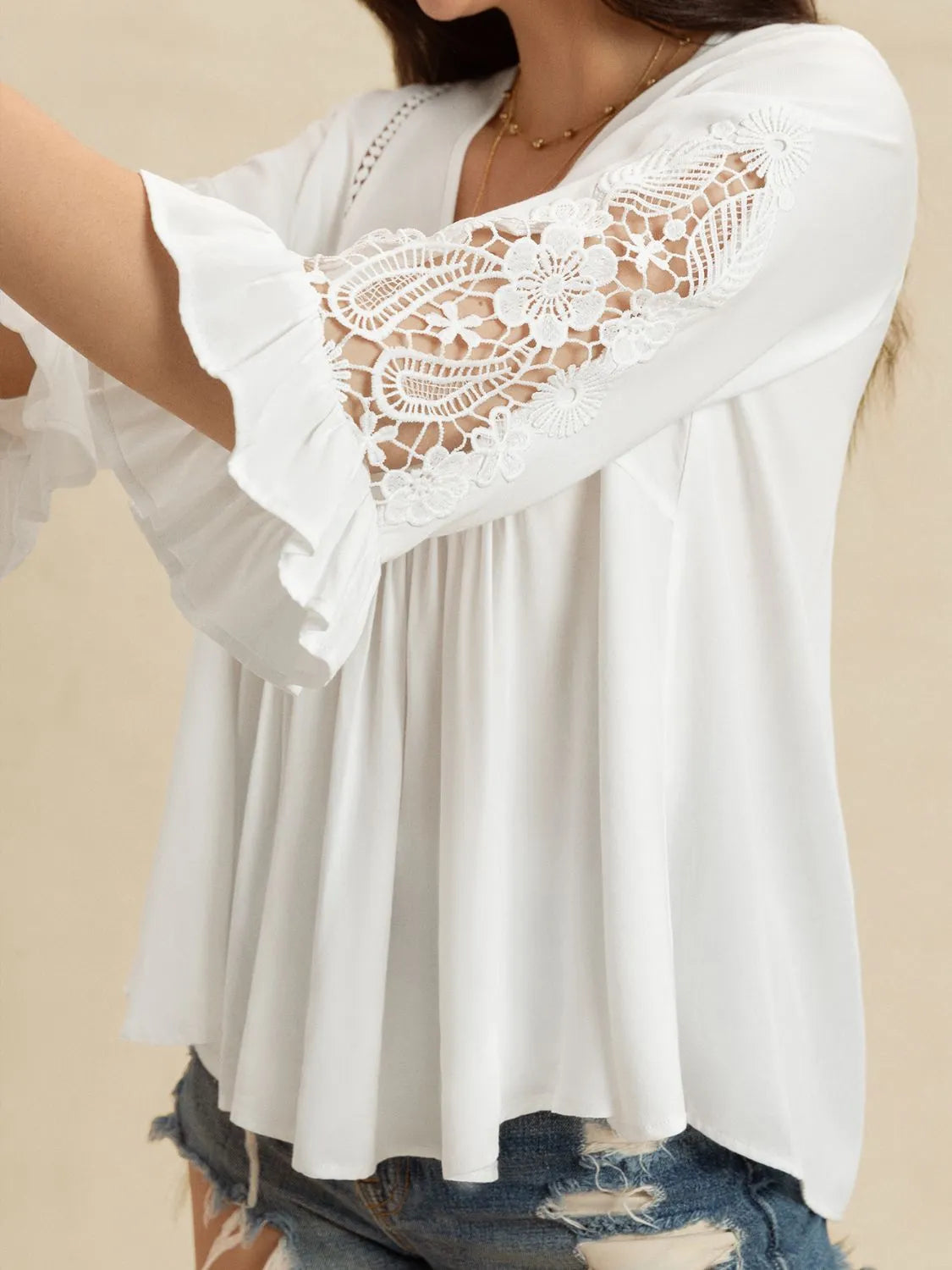 White blouse with lace sleeves on a beige background