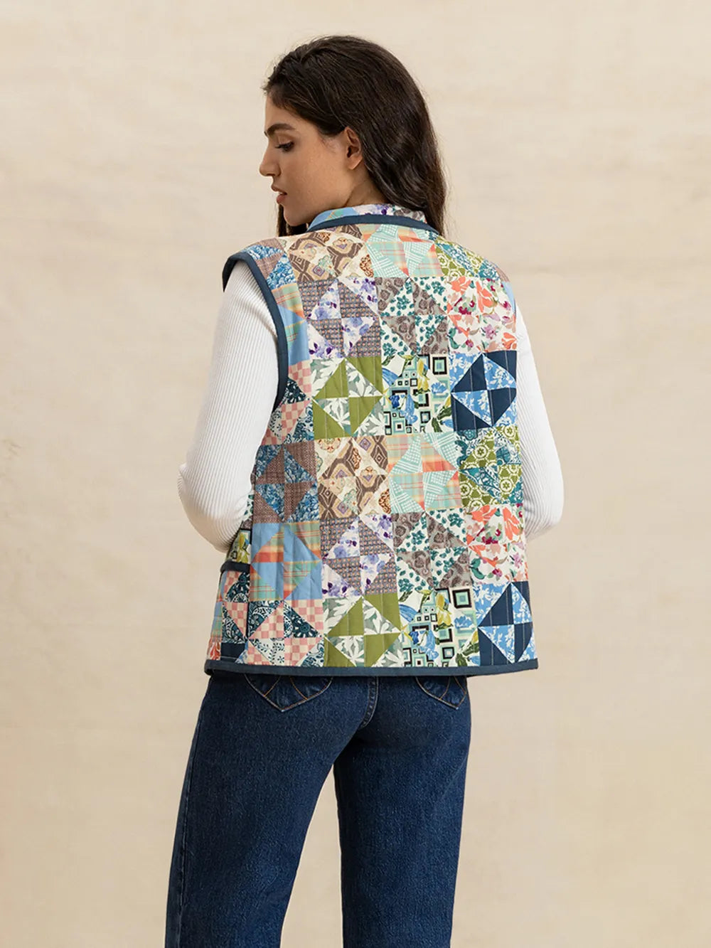Person wearing a colorful quilted vest on a beige background