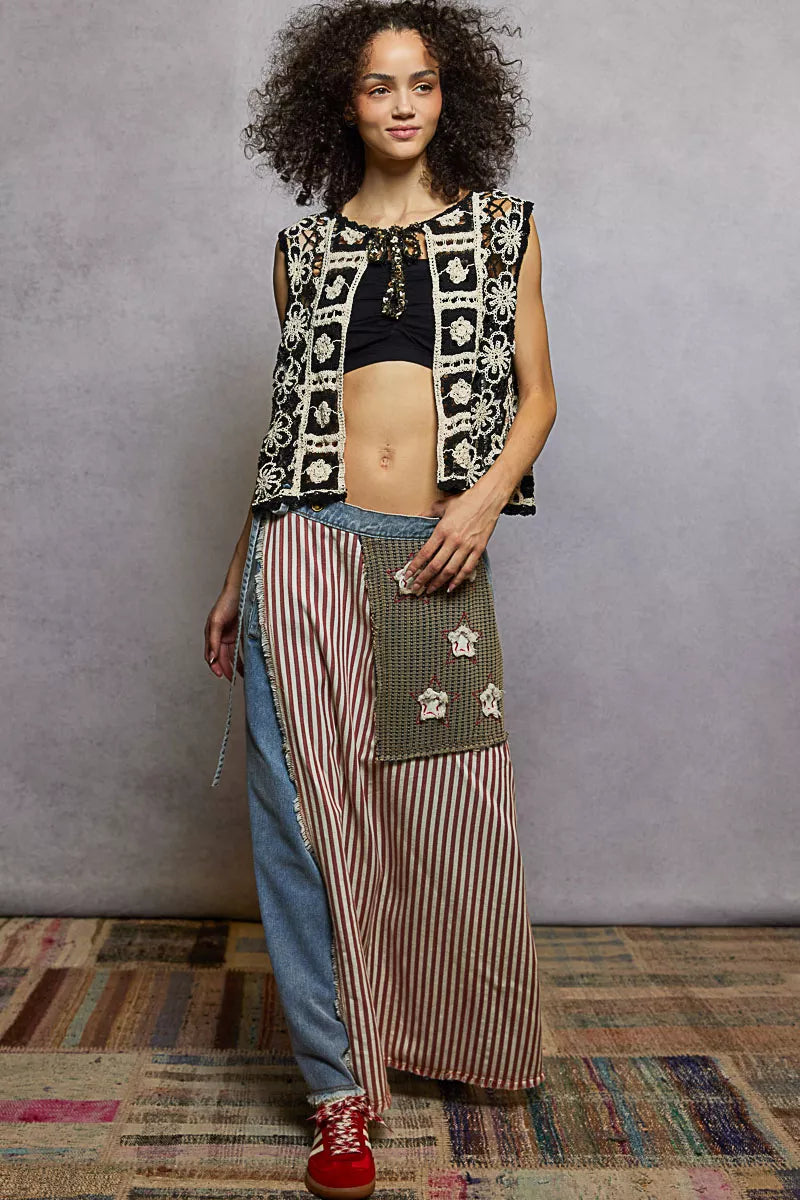 Woman wearing a patterned vest and long skirt with a textured floor and wall background