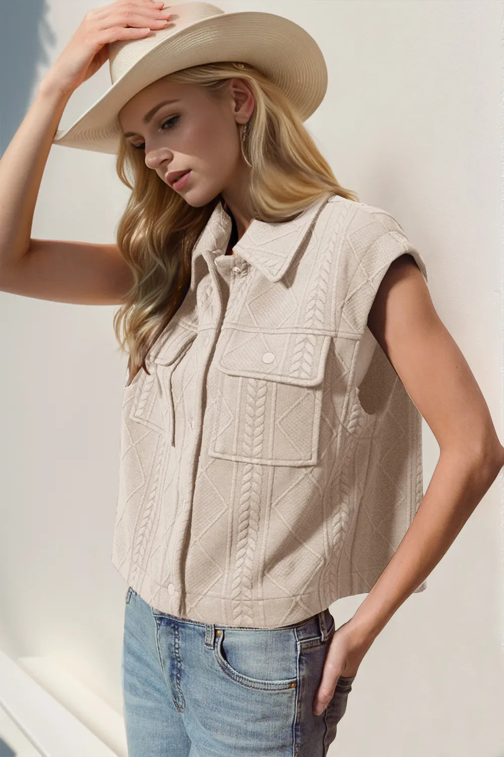 Woman wearing a beige vest, white shirt, and blue jeans with a white background