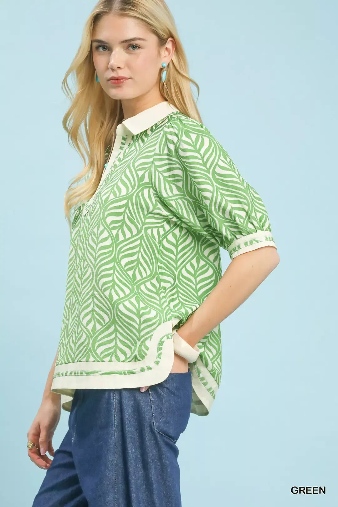 Woman wearing a green patterned blouse with white collar against a light blue background