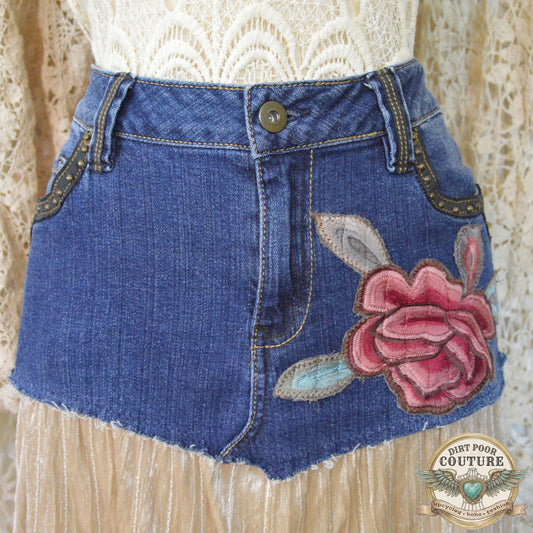 A detailed shot of the intricate red and pink peony embroidered applique below the studded denim pocket