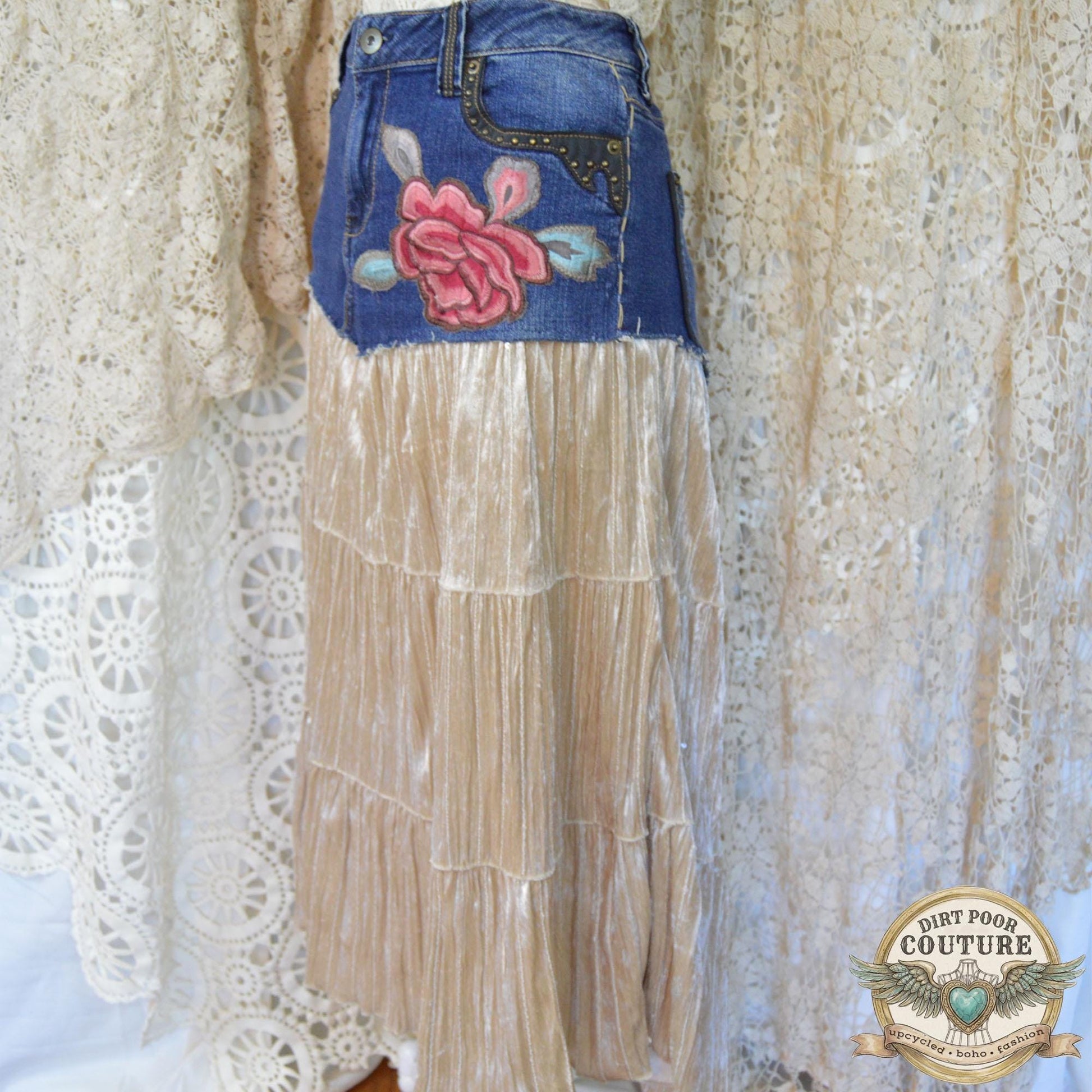 A handmade maxi skirt on a mannequin, combining a studded denim top with a flowing, champagne-colored velvet skirt featuring a red peony embroidery below the left pocket.