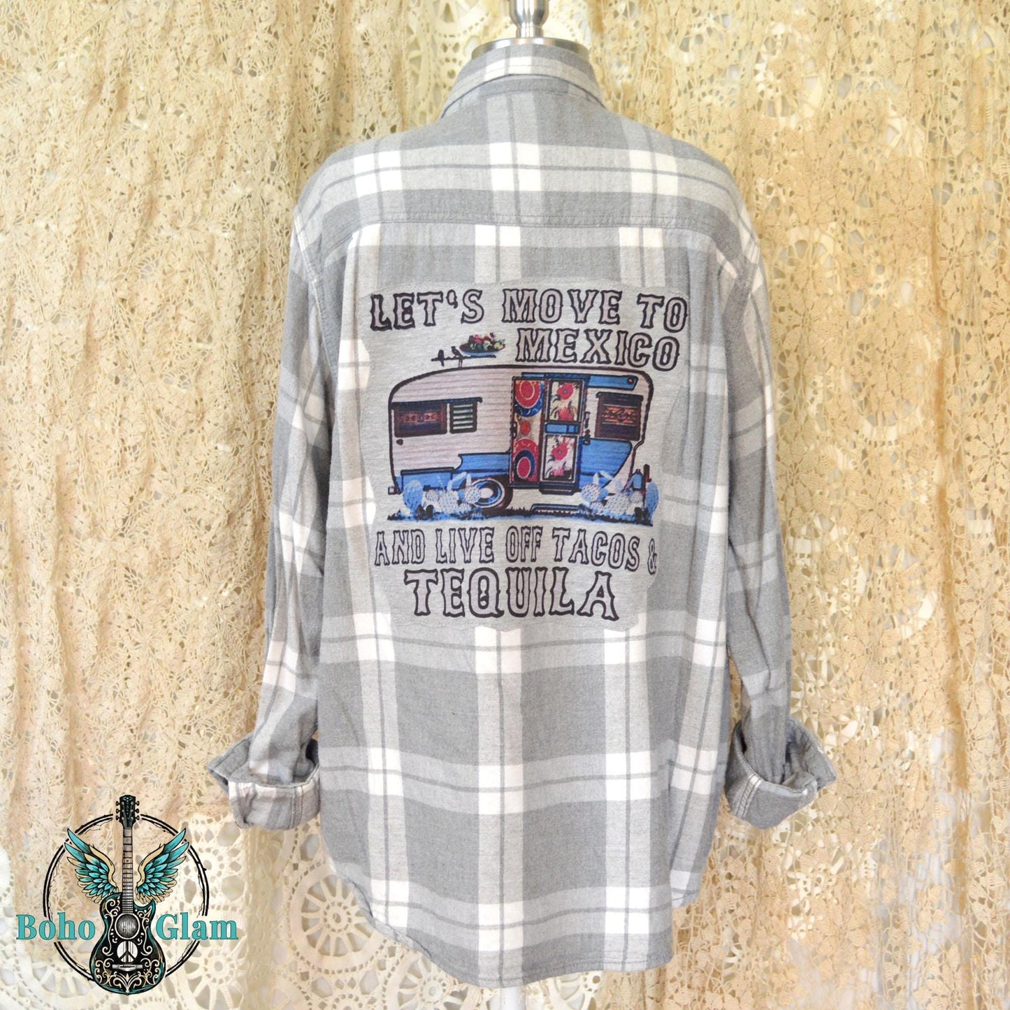 Back View: A grey and white plaid flannel shirt featuring a large graphic applique of a vintage blue camper with text about moving to Mexico for tacos and tequila