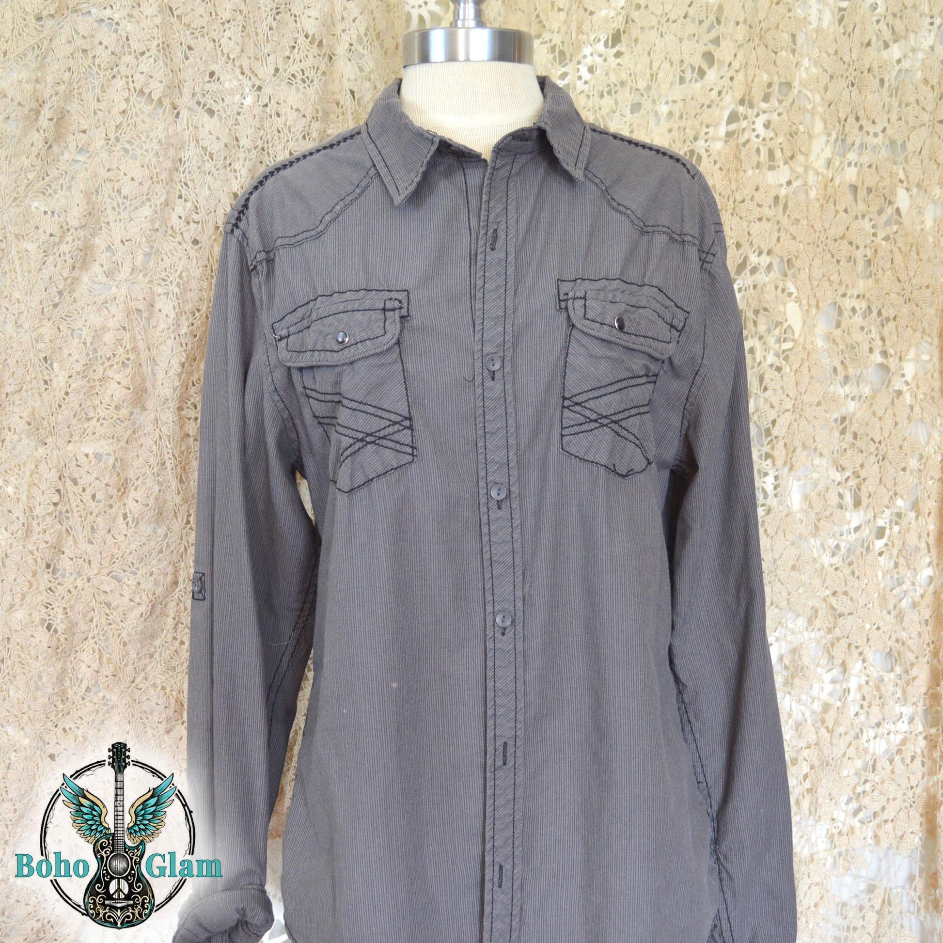 The front of a gray corduroy western shirt on a mannequin showing double chest pockets with black contrast stitching and silver snap buttons.