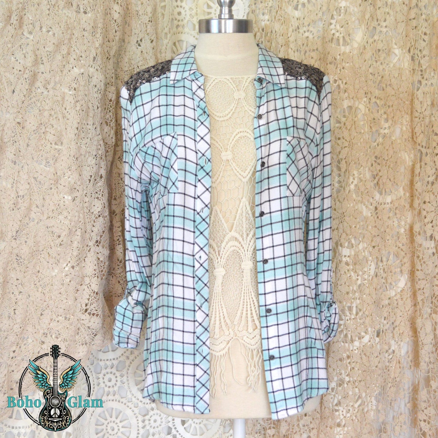Front on Mannequin: Front view of the open plaid shirt on a mannequin layered over a lace top showing the silver sequin shoulder accents.