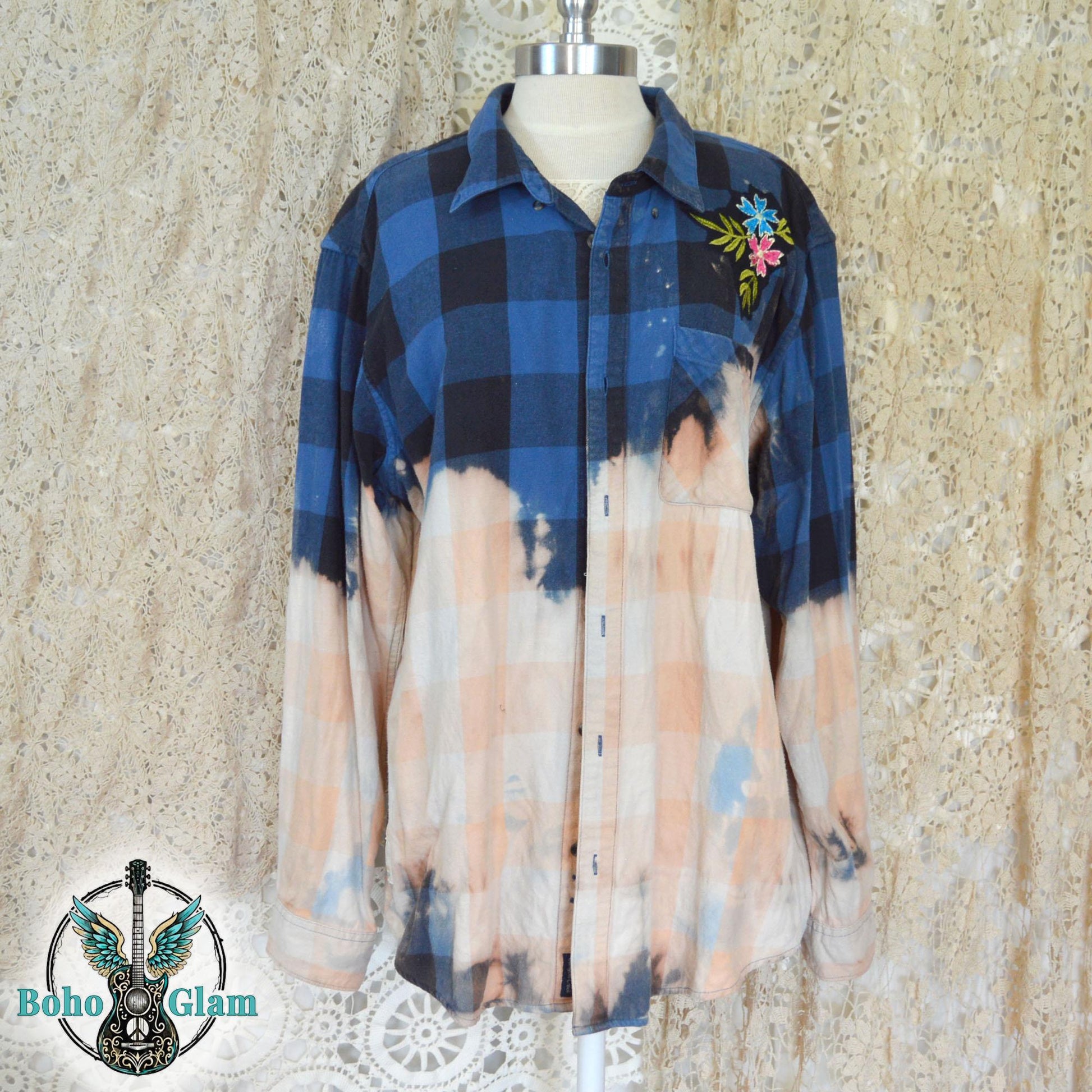Front View: The front of a button-down bleached flannel shirt on a mannequin showing the oversized fit and the floral embroidery on the shoulder.