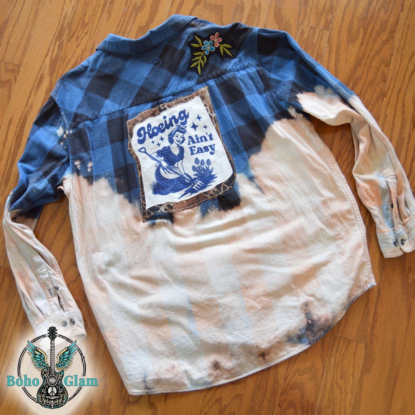 Flat Lay: The upcycled garden-themed flannel laid flat on a wood floor to show the full scale of the bleaching and back applique design.