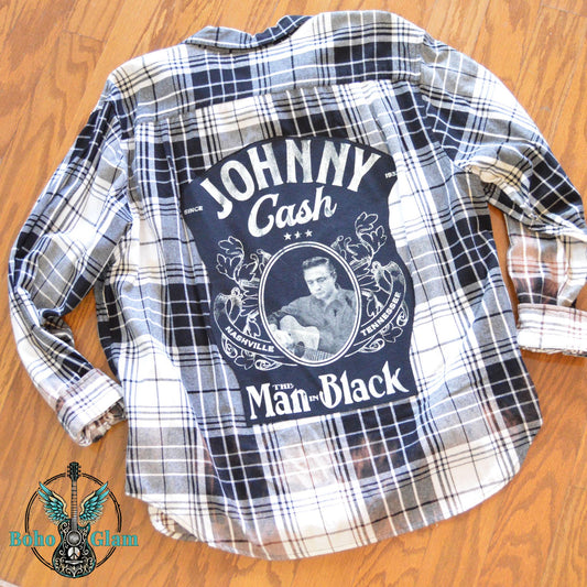 Flat Lay Back: The upcycled Johnny Cash flannel laid flat on a wood surface to show the full scale of the graphic and the custom bleaching.