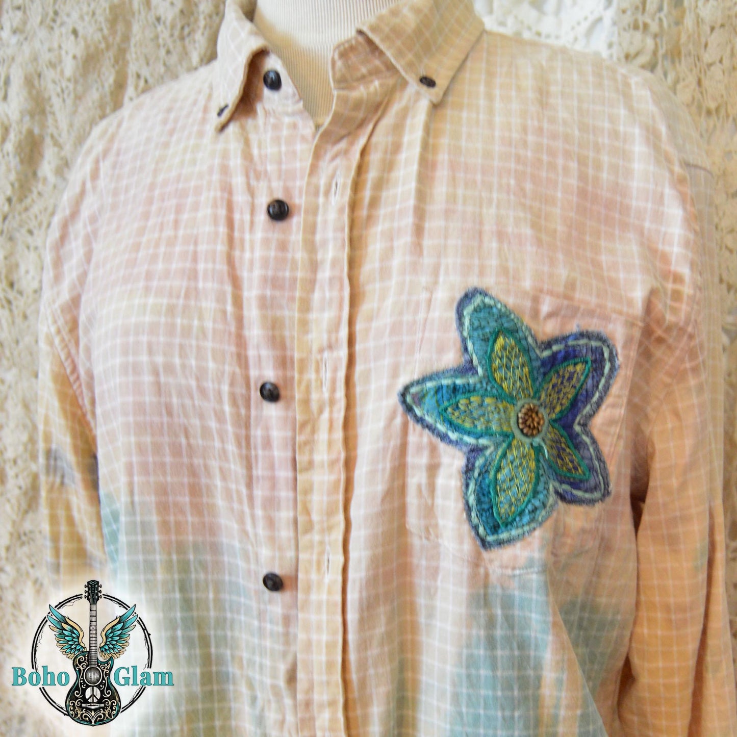 Front Detail: A close-up of a yellow grid pattern shirt featuring a vibrant teal and green embroidered floral applique over the chest pocket.