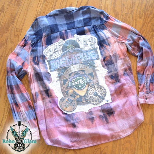 Flat Lay Back: The back of the bleached flannel laid flat, featuring a large, colorful Memphis Hard Rock Cafe graphic with guitars and music notes.