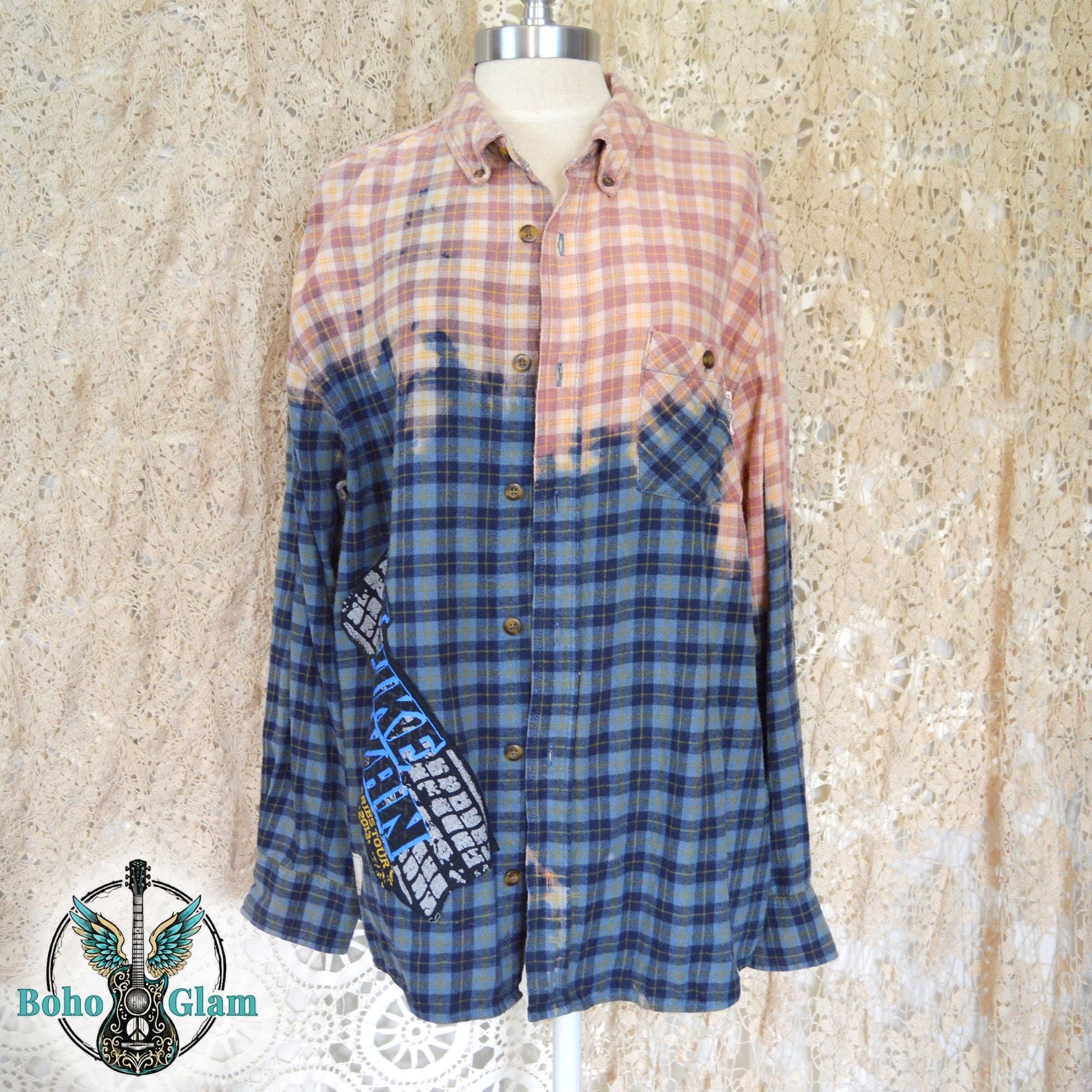 Front View: A blue plaid flannel shirt on a mannequin featuring a dip bleached peach top half and a Luke Bryan tour logo applique on the bottom right.