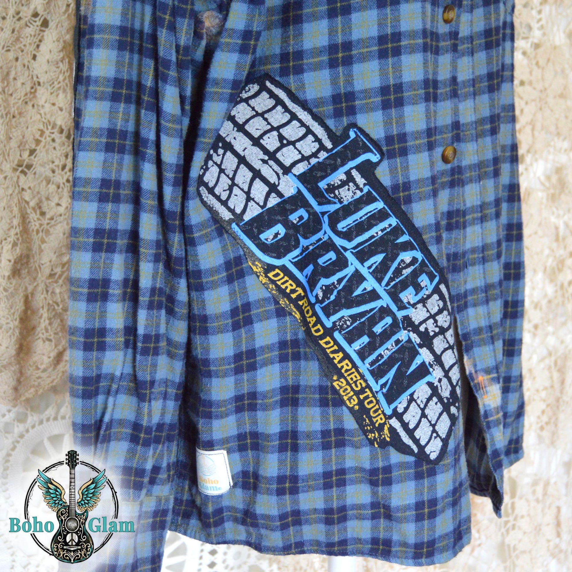 Front Close-up: A detailed shot of the front applique showing the Luke Bryan Dirt Road Diaries Tour 2013 logo with a tire track design on the blue plaid fabric.