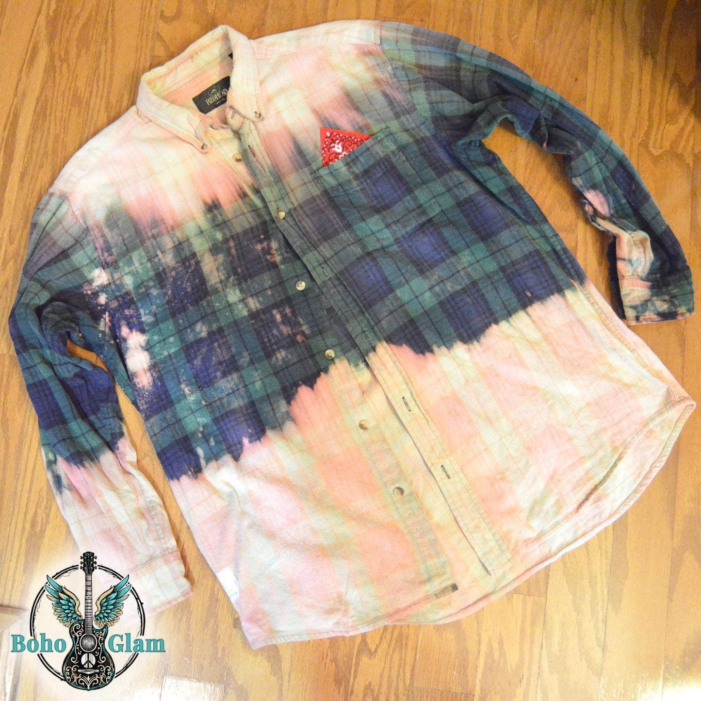 Flat Lay Front: The front of a green and navy plaid flannel laid flat, showing a dramatic horizontal bleach line and a red bandana pocket accent.