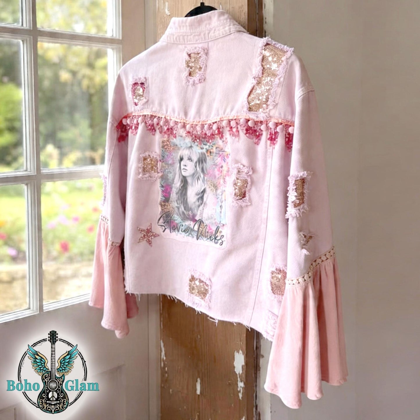 Back view of pink Stevie Nicks inspired denim jacket with watercolor portrait graphic, pom trim detail, distressed patches and sequin accents, one of a kind boho glam jacket