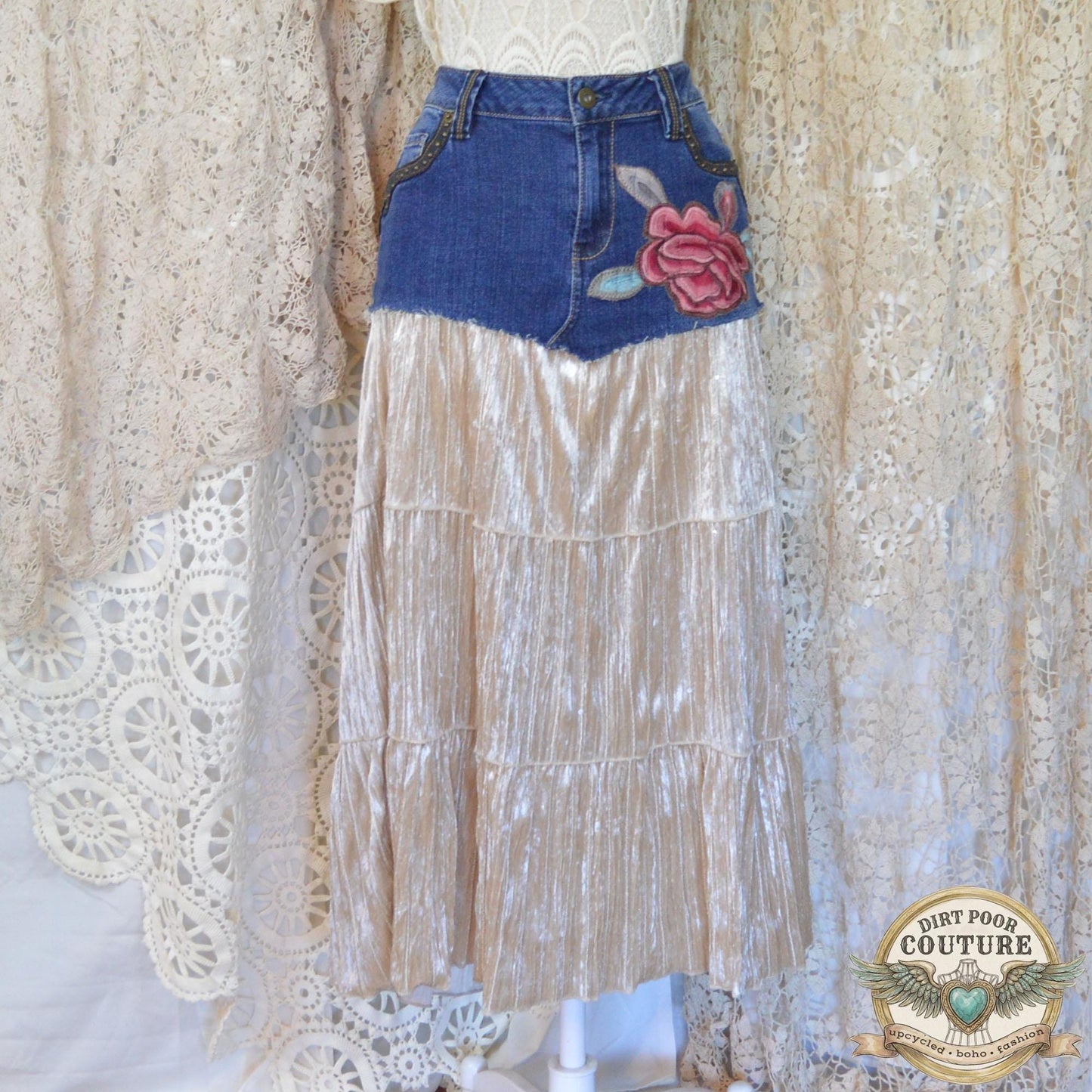 A handmade maxi skirt on a mannequin, combining a studded denim top with a flowing, champagne-colored velvet skirt featuring a red peony embroidery below the left pocket.