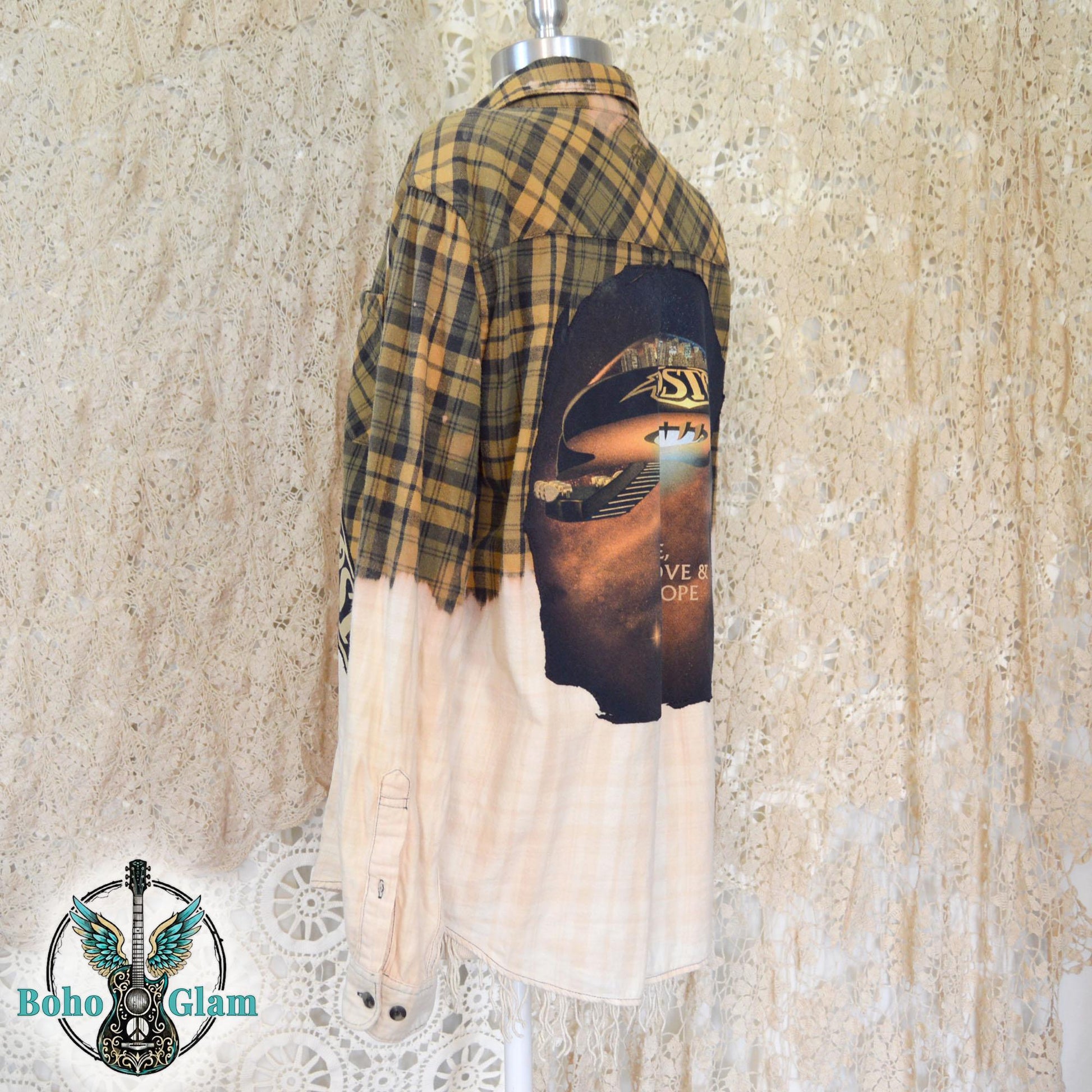 Back View: A yellow and black plaid flannel shirt with a bleached white bottom half and a large circular Boston band graphic appliqued on the back
