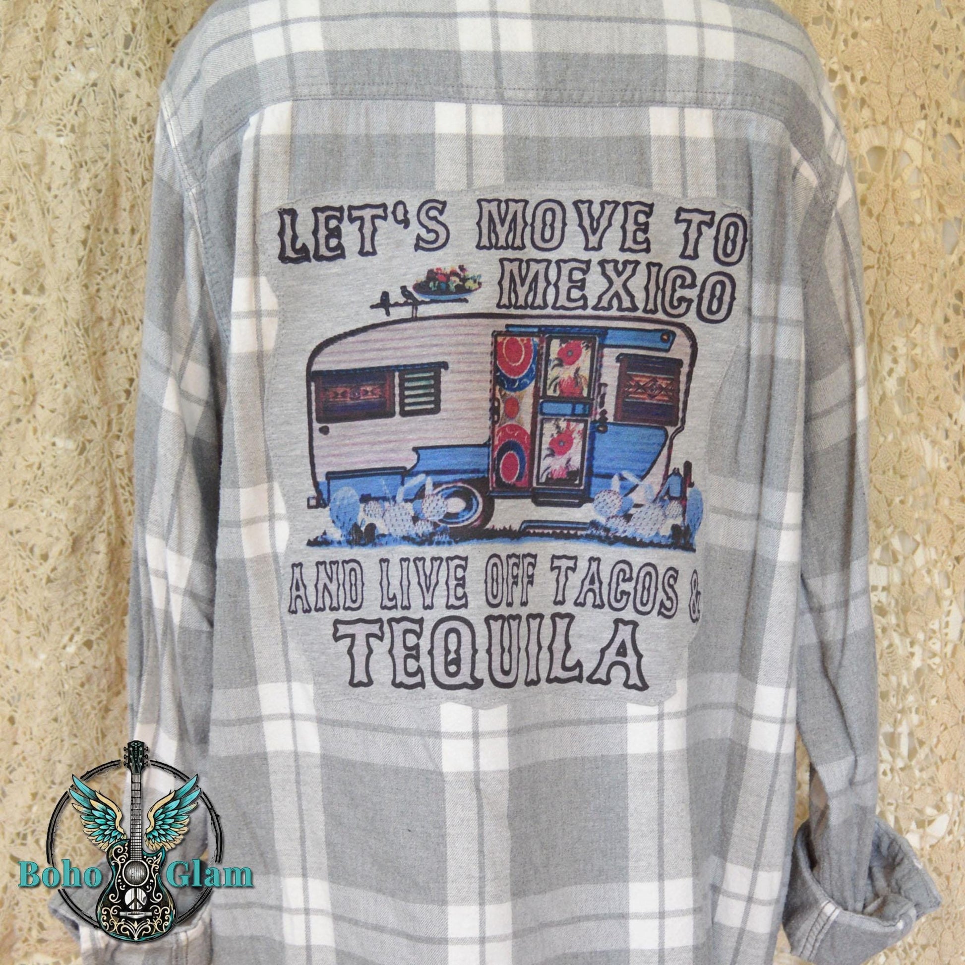 Back View: A grey and white plaid flannel shirt featuring a large graphic applique of a vintage blue camper with text about moving to Mexico for tacos and tequila