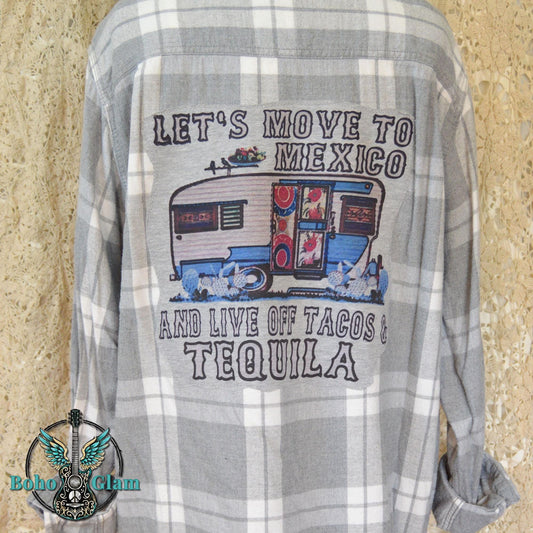 Back View: A grey and white plaid flannel shirt featuring a large graphic applique of a vintage blue camper with text about moving to Mexico for tacos and tequila